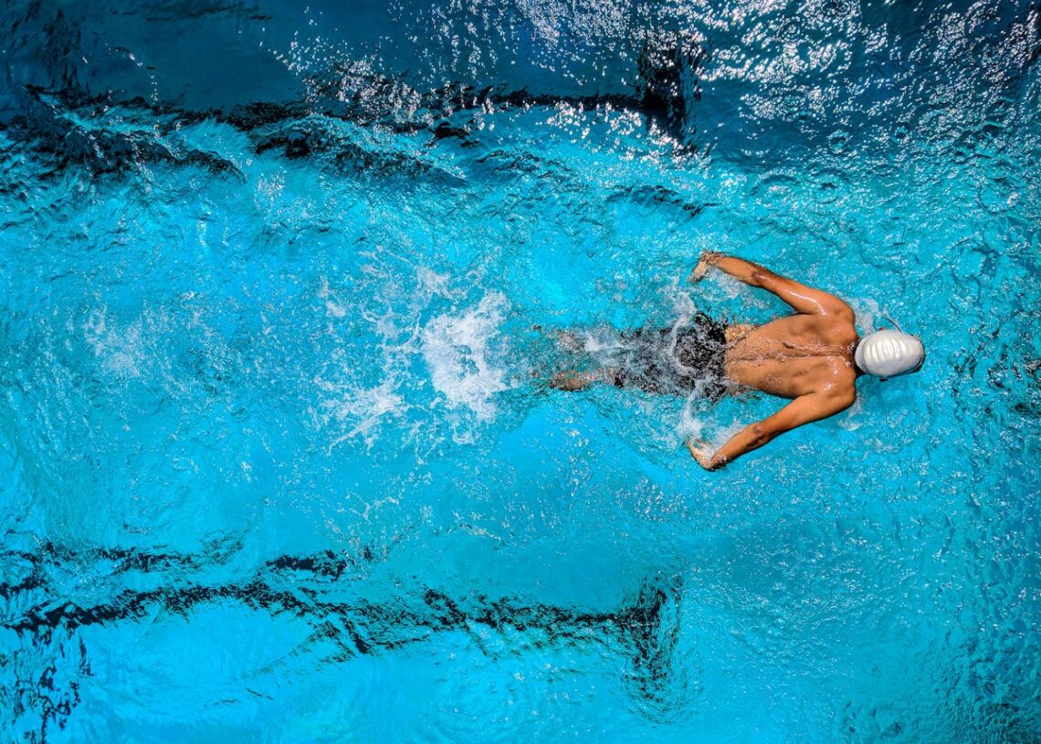 Persona nadando estilo crol en piscina